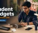 Modern university student using essential gadgets including a power bank, wireless earbuds, smartwatch, laptop stand, study lamp, and rechargeable fan in Bangladesh.
